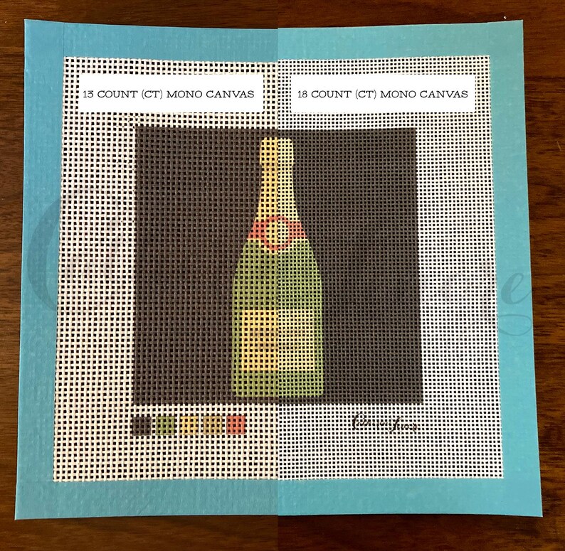 May include: Two pieces of white Aida cloth with a green, yellow, and red champagne bottle design printed on them. The cloth is labeled "13 COUNT (CT) MONO CANVAS" and "18 COUNT (CT) MONO CANVAS".