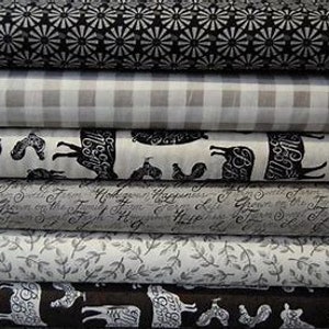 May include: Stack of eight fabric swatches in black and white patterns. The patterns include a black and white floral print, a gingham check, a black and white animal print, a script print, a leaf print, and a black and white animal print.