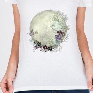 May include: A white t-shirt with a watercolor design of a moon surrounded by flowers and a butterfly.