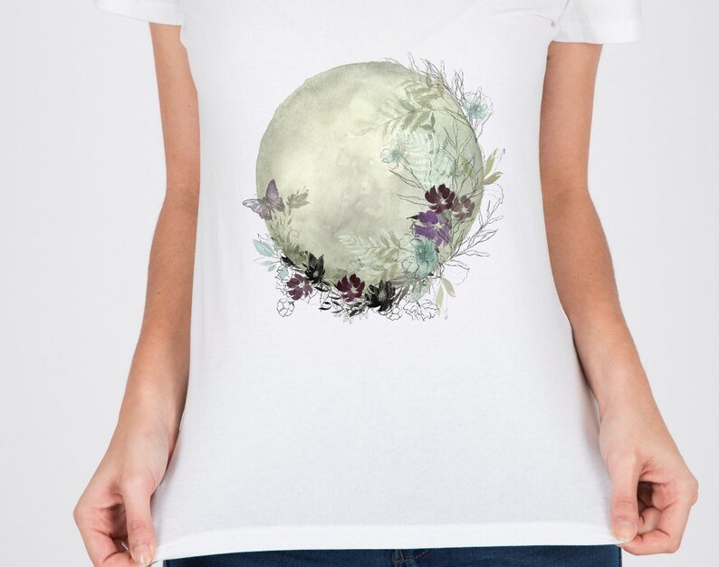 May include: A white t-shirt with a watercolor design of a moon surrounded by flowers and a butterfly.