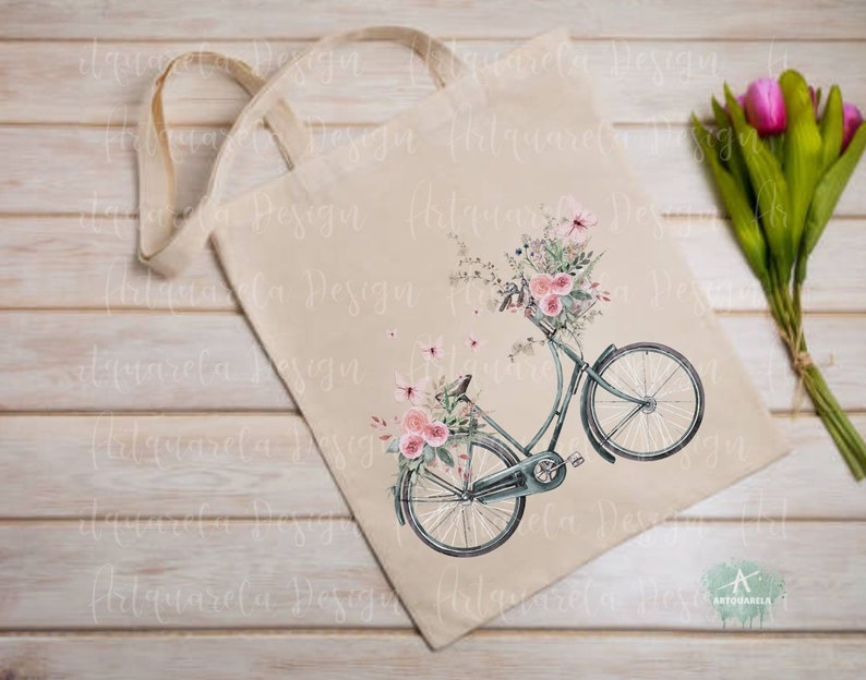 Pu&ograve; includere: Una borsa di tela bianca con un design floreale e una bicicletta vintage con un cestino pieno di fiori. La bicicletta &egrave; blu e ha una sella marrone. I fiori sono rosa e bianchi.