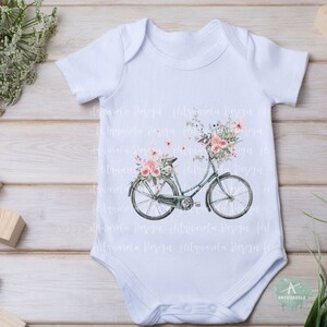 Pu&ograve; includere: Body bianco per neonato con un design floreale di una bicicletta con fiori rosa nel cestino.