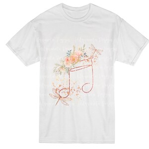 May include: A white t-shirt with a floral and dragonfly design. The design features a musical note with a floral arrangement and two dragonflies. The design is in shades of pink, orange, and brown.