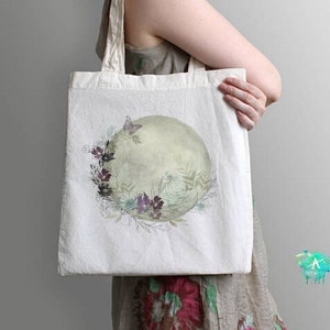 May include: A white tote bag with a floral design featuring a green and white circle with a butterfly and purple flowers.