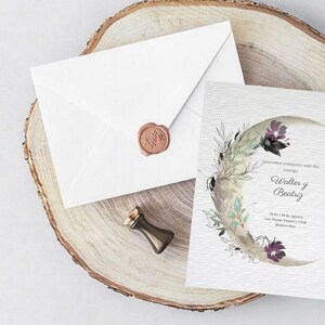 May include: A wedding invitation with a watercolor illustration of a crescent moon with floral details. The invitation is for Walter and Beatriz, and it states the date and location of the wedding. The invitation is on a wooden surface with a white envelope and a wax seal.