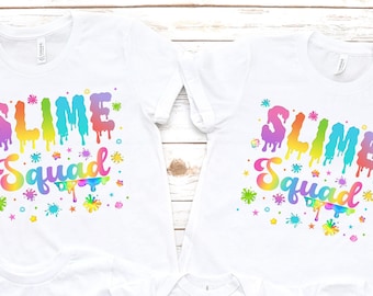 May include: A set of four white t-shirts with a slime theme. The shirts feature the text "Slime Squad" in rainbow colors with dripping slime and colorful splatters. One shirt has the text "This Slime Queen Maya is 10" with a rainbow crown and a number 10 balloon.