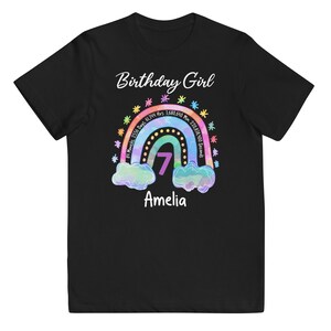 May include: Black t-shirt with a rainbow design and the text "Birthday Girl" and "Amelia". The rainbow has a number 7 in the center and text around it that reads "81 Months, 2556 Days, 61,344 Hrs, 3,680,640 Min, 220,838,400 Seconds".