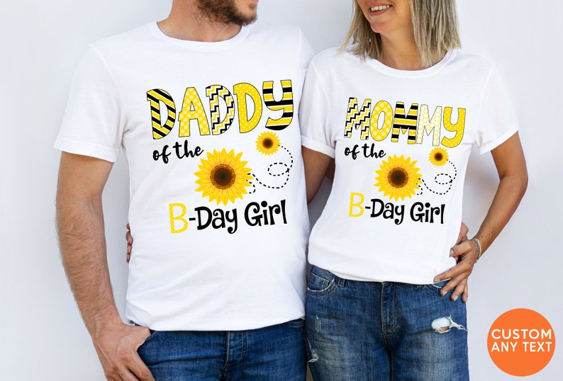 Peut inclure: Deux t-shirts blancs avec des motifs de tournesols assortis. L'un porte l'inscription "DADDY of the B-Day Girl" en lettres jaunes et noires, avec un motif de tournesol. L'autre dit "MOMMY of the B-Day Girl".