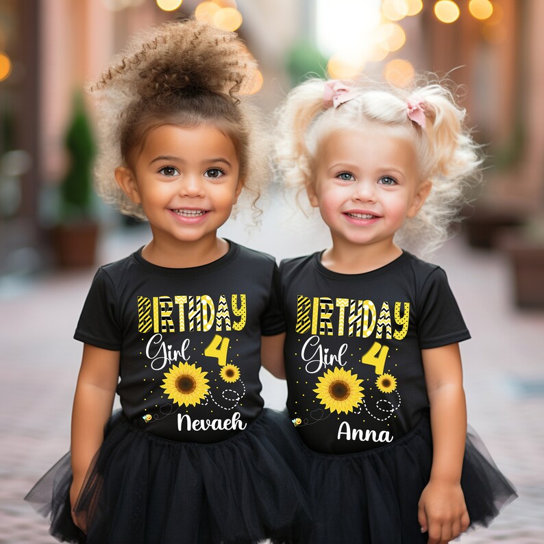 Peut inclure: Deux jeunes filles portant des t-shirts noirs assortis avec "Birthday Girl 4" et des motifs de tournesols. Chaque chemise porte un nom imprim&eacute; sous le tournesol. Elles portent &eacute;galement des jupes en tulle noires.