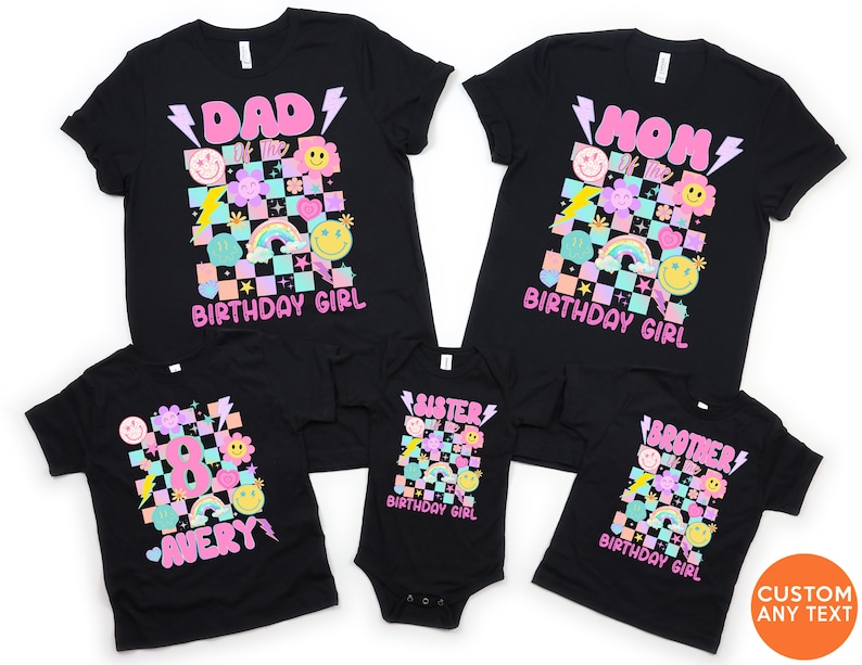 May include: Black t-shirts with colourful retro graphics. Designs include "DAD," "MOM," "8," "SISTER," and "BROTHER" with "BIRTHDAY GIRL" text. The shirts feature smiley faces, rainbows, and lightning bolts. The name "AVERY" is also displayed.