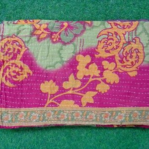 Pode incluir: T&ecirc;xtil dobrado com um design floral em tons de rosa, verde e laranja. A camada superior &eacute; rosa vibrante, transicionando para um verde claro com padr&otilde;es florais laranja. As bordas s&atilde;o costuradas com fio branco, e a borda inferior apresenta um padr&atilde;o floral verde e laranja.
