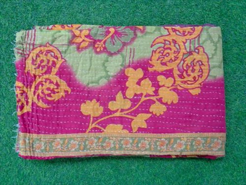 Pode incluir: T&ecirc;xtil dobrado com um design floral em tons de rosa, verde e laranja. A camada superior &eacute; rosa vibrante, transicionando para um verde claro com padr&otilde;es florais laranja. As bordas s&atilde;o costuradas com fio branco, e a borda inferior apresenta um padr&atilde;o floral verde e laranja.