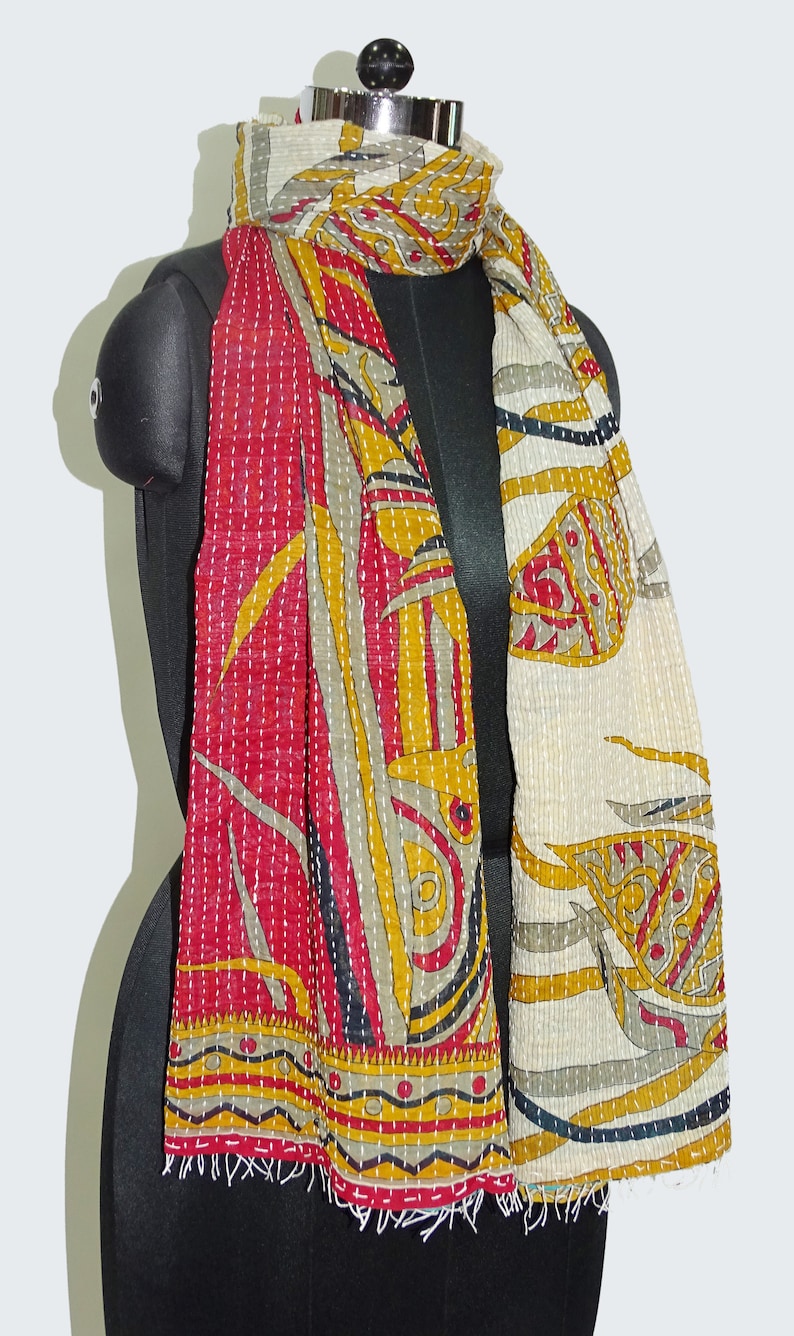 May include: A red, white and gold kantha scarf with a floral pattern. The scarf is quilted and has a fringed edge.