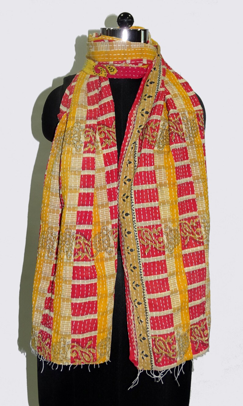 May include: A yellow and red kantha quilted scarf with a geometric pattern. The scarf is made of cotton and has a fringed edge.