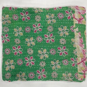 Pode incluir: T&ecirc;xtil verde dobrado com um padr&atilde;o floral. As flores s&atilde;o em tons de rosa, amarelo e branco, espalhadas pelo tecido. As bordas t&ecirc;m uma borda estampada. &Eacute; provavelmente um cobertor ou colcha, possivelmente costurado &agrave; m&atilde;o.
