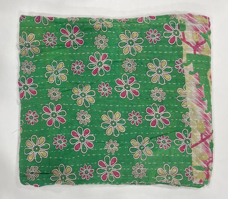 Pode incluir: T&ecirc;xtil verde dobrado com um padr&atilde;o floral. As flores s&atilde;o em tons de rosa, amarelo e branco, espalhadas pelo tecido. As bordas t&ecirc;m uma borda estampada. &Eacute; provavelmente um cobertor ou colcha, possivelmente costurado &agrave; m&atilde;o.