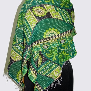 May include: A green and yellow kantha quilt scarf with a floral pattern. The scarf is made of cotton and has a fringed edge.