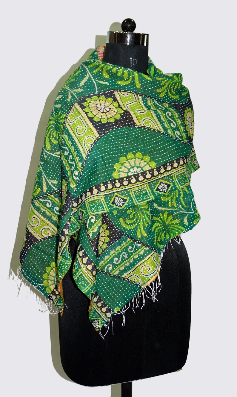 May include: A green and yellow kantha quilt scarf with a floral pattern. The scarf is made of cotton and has a fringed edge.