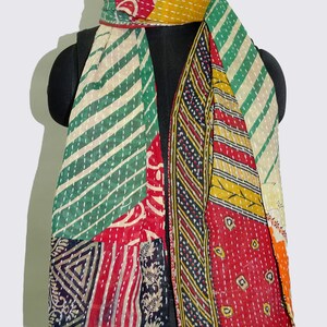 May include: A colourful patchwork scarf made from recycled saris. The scarf features a variety of patterns and colours, including green, red, yellow, and black. The scarf is fringed on the edges.