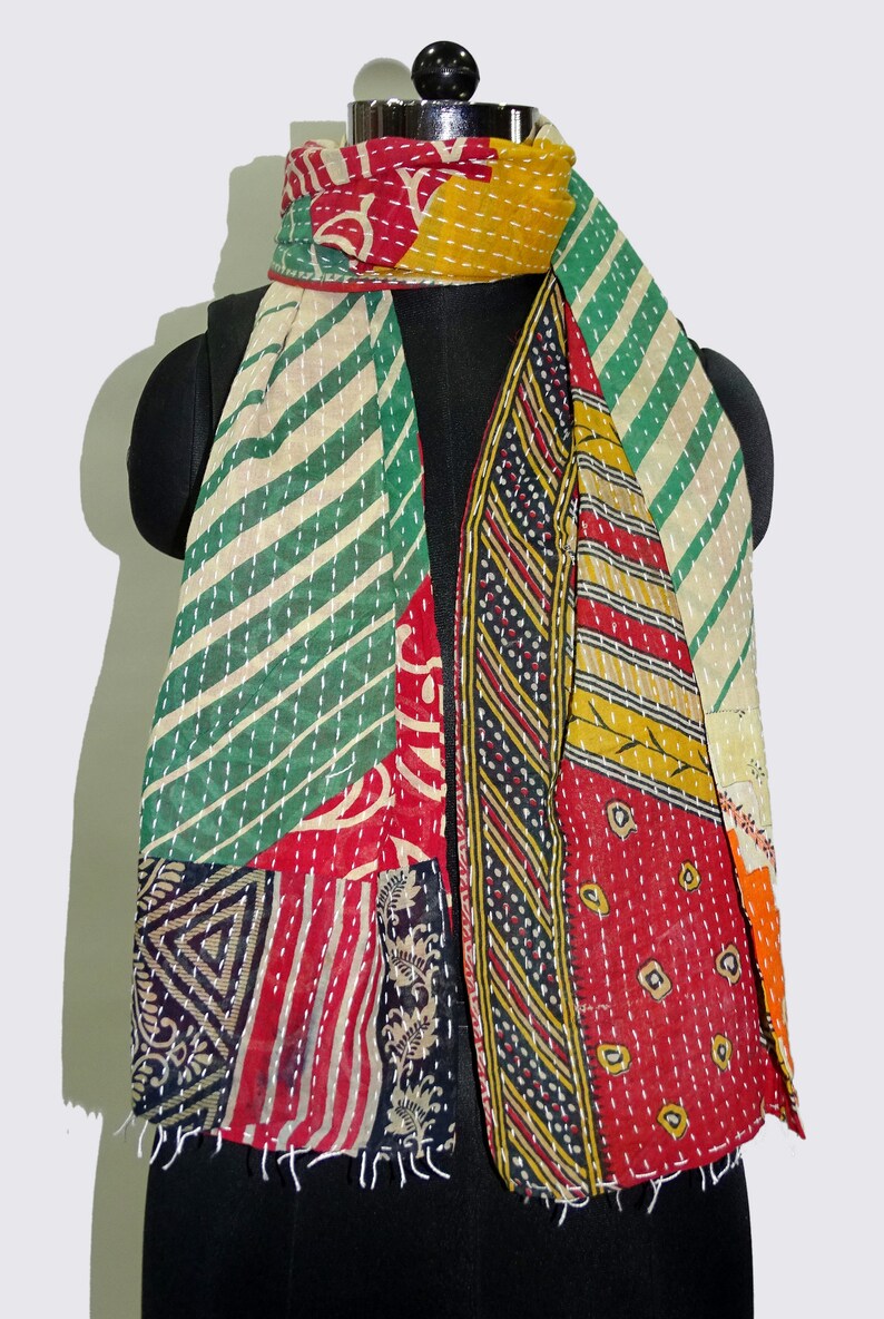 May include: A colourful patchwork scarf made from recycled saris. The scarf features a variety of patterns and colours, including green, red, yellow, and black. The scarf is fringed on the edges.