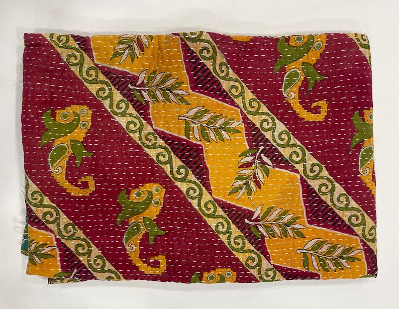 Pode incluir: T&ecirc;xtil dobrado com um padr&atilde;o repetido de cavalos-marinhos e motivos de folhas. O fundo &eacute; vermelho escuro, com detalhes diagonais amarelos e verdes. As bordas s&atilde;o adornadas com uma borda decorativa.