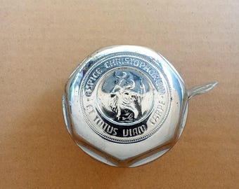 May include: A circular chrome bicycle bell featuring an embossed central figure of Saint Christopher carrying a child. The outer rim displays the Latin inscription "RESPICE CHRISTOPHORUM ET TUTA VIAM CARPE" in raised lettering with a beaded border.