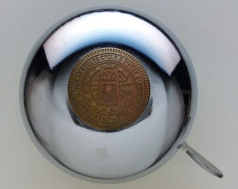 May include: A silver bicycle bell with a gold-colored emblem that reads "The Hercules Cycle & Motor Co. Ltd. Birmingham".