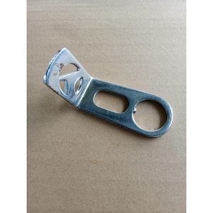 May include: A silver-colored metal bracket featuring an L-shaped design with a flat, elongated arm. The arm contains a rectangular cutout and a circular hole at the end, while the angled section includes a triangular cutout with rounded corners.
