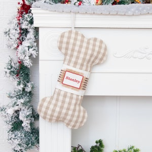 May include: A beige and white gingham dog bone-shaped Christmas stocking with a burlap tag that says "Stanley" in red embroidery.