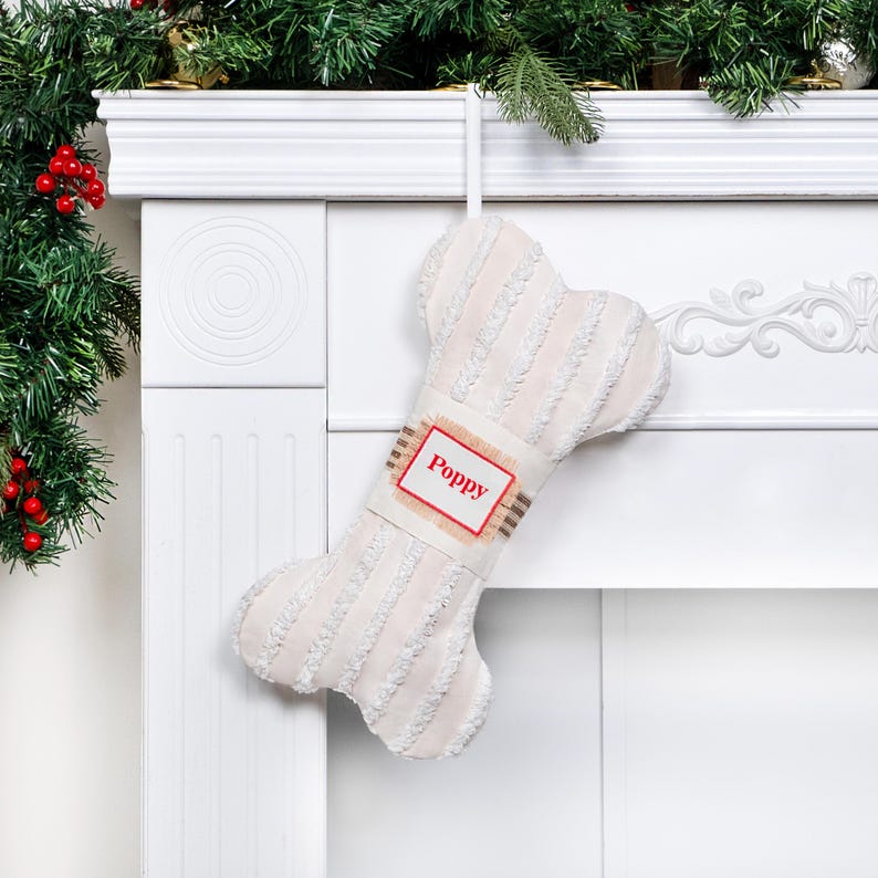 May include: White plush dog bone stocking with a red and white personalized tag that says "Poppy".