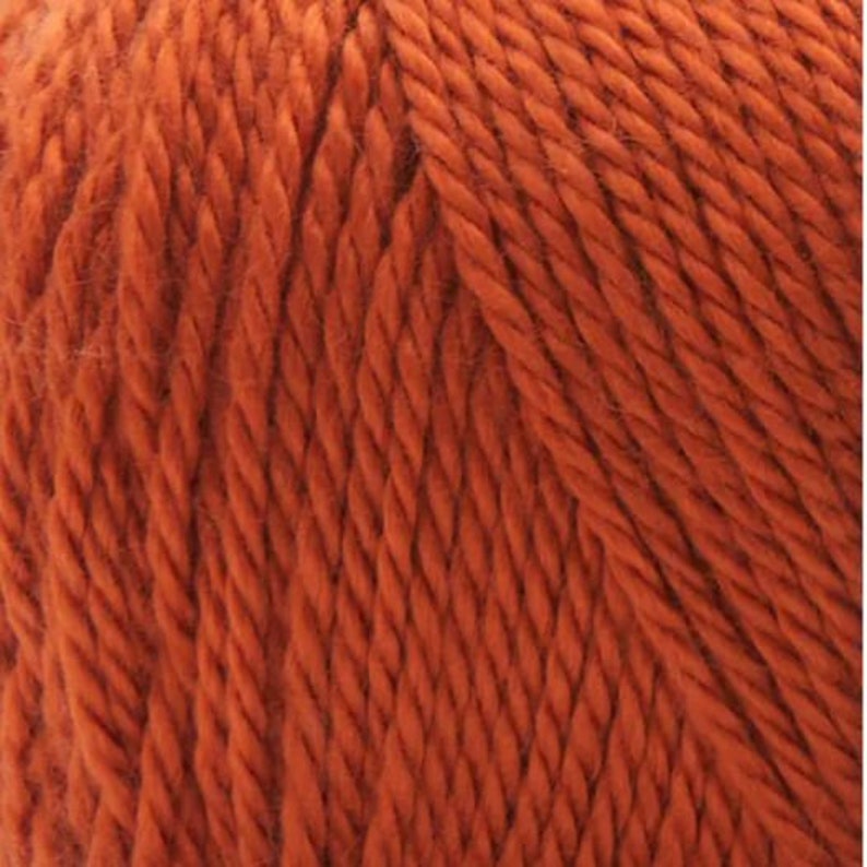 K&ouml;nnte beinhalten: Nahaufnahme eines Kn&auml;uels orangefarbenes Garn. Das Garn ist weich und flauschig und hat eine leicht strukturierte Oberfl&auml;che.
