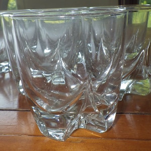 May include: Set of six clear glass tumblers with a unique, textured design. The glasses are stacked on a wooden table.