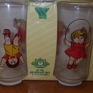 May include: Set of four 12-ounce glass beverage glasses with colourful cartoon illustrations of children. The glasses are packaged in a yellow and white box with the text "12 oz. Beverage Set 4 - 12 oz. Glasses".