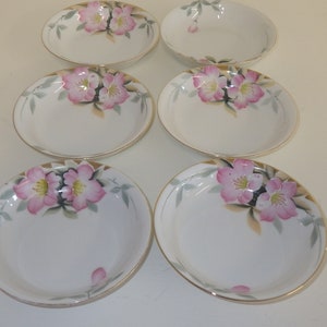 Puede incluir: Juego de seis cuencos de cerámica blanca con diseños florales rosas y verdes. Los cuencos tienen un borde dorado y son perfectos para servir aperitivos o postres.