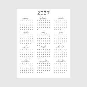 Peut inclure: Calendrier minimaliste de 2027 imprimé sur papier blanc. Le calendrier présente un design simple avec l'année en haut et des présentations mensuelles dans un format de grille. Chaque mois est étiqueté avec une police manuscrite.