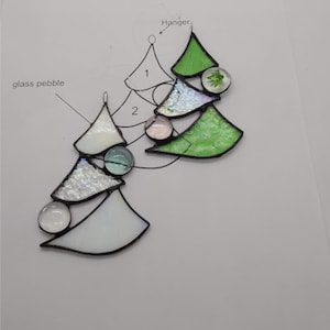 Peut inclure: Un modèle de sapin de Noël en vitrail avec des instructions de montage. Le modèle comprend deux sapins, un blanc et un vert, avec des galets de verre et un cintre.