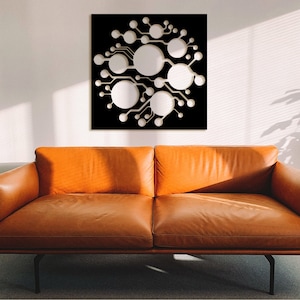 May include: A black square wall decor with a white abstract design of circles and lines. The design resembles a circuit board or a network.