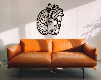 May include: Black metal wall art depicting a brain and a heart, hanging on a white wall above a brown leather couch.