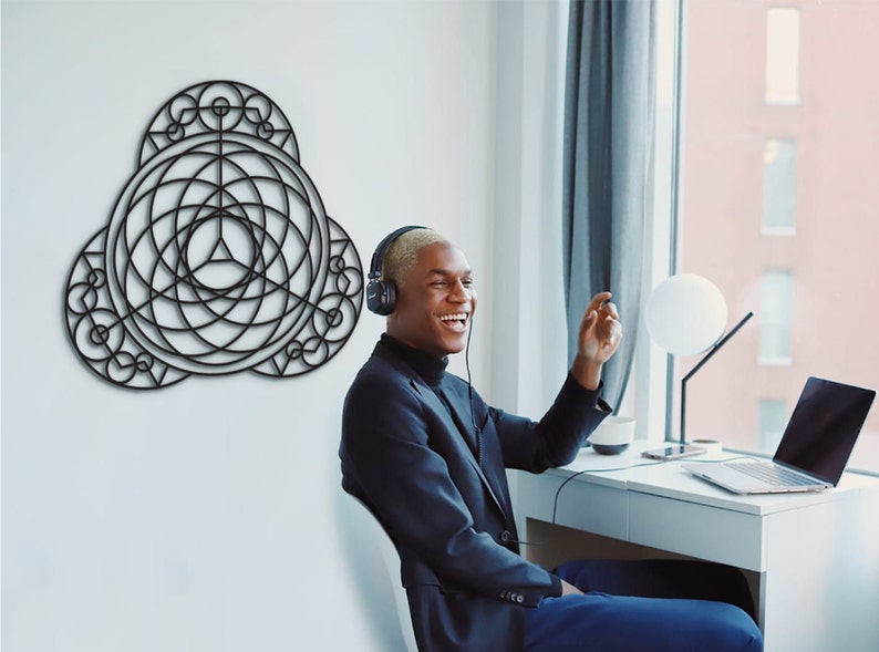 Puede incluir: Una persona con auriculares est&aacute; sentada en un escritorio frente a una ventana, sonriendo y mirando hacia un lado. Un dise&ntilde;o geom&eacute;trico negro est&aacute; en la pared detr&aacute;s de ella.