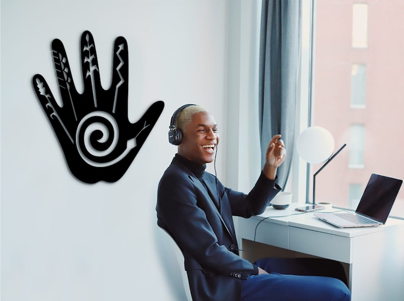 May include: A black silhouette of a hand with a spiral design in the palm and various lines and shapes on the fingers. A person wearing headphones is sitting in front of a window and a desk with a laptop.