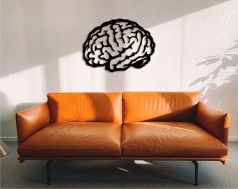 May include: A black silhouette of a human brain on a white wall above a brown leather couch.