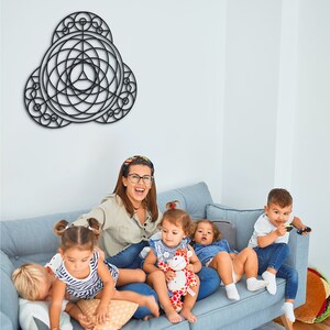 Puede incluir: Un grupo de ni&ntilde;os y una mujer adulta est&aacute;n sentados en un sof&aacute; azul claro. La mujer lleva una camisa azul claro y gafas. Los ni&ntilde;os llevan ropa de varios colores. Hay una obra de arte de pared geom&eacute;trica negra colgada en la pared detr&aacute;s del sof&aacute;.