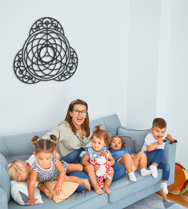 Puede incluir: Un grupo de ni&ntilde;os y una mujer adulta est&aacute;n sentados en un sof&aacute; azul claro. La mujer lleva una camisa azul claro y gafas. Los ni&ntilde;os llevan ropa de varios colores. Hay una obra de arte de pared geom&eacute;trica negra colgada en la pared detr&aacute;s del sof&aacute;.