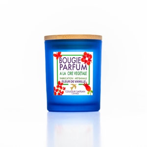 Puede incluir: Un tarro de vela azul con tapa de madera. La etiqueta dice "Bougie Parfum A La Cire Vegetale Fabrication Artisanale Fleur De Vanille Couleur Safran Cannes".