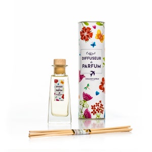 Op de afbeelding: Een parfumdiffuserset met een heldere glazen fles met een houten stopper, een etiket en een decoratieve cilindrische doos. De doos en het etiket zijn voorzien van bloemen- en vlinderontwerpen. De set bevat houten diffuserstokjes. Het etiket leest "Diffuser de Parfum".