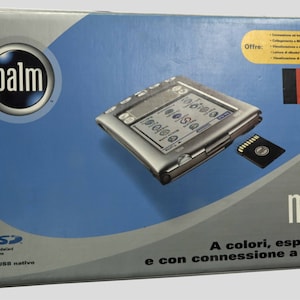 Può includere: Un computer palmare Palm m505 Palmare argentato con uno schermo a colori e uno slot per schede di memoria. La scatola presenta il testo "A colori, espandibile e con connessione a Internet".