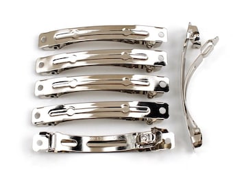 Op de afbeelding: Een set van zeven zilveren metalen haarclips. Vijf clips zijn recht en twee zijn gebogen.