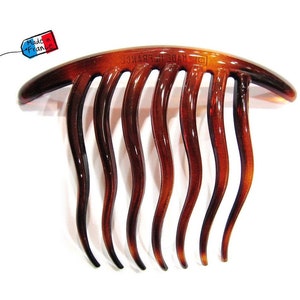 May include: A brown plastic hair comb with seven wavy teeth. The comb is curved and has the text "MADE IN FRANCE" on the top.