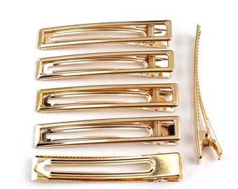 May include: Set of six gold metal hair clips. Five clips are rectangular and one is a longer, thinner clip.