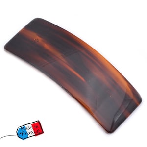 Könnte beinhalten: Eine rechteckige Haarspange mit Schildpattmuster. Die Spange ist gebogen und hat eine glänzende Oberfläche. Das Bild enthält ein Etikett mit der Aufschrift "Made in France".